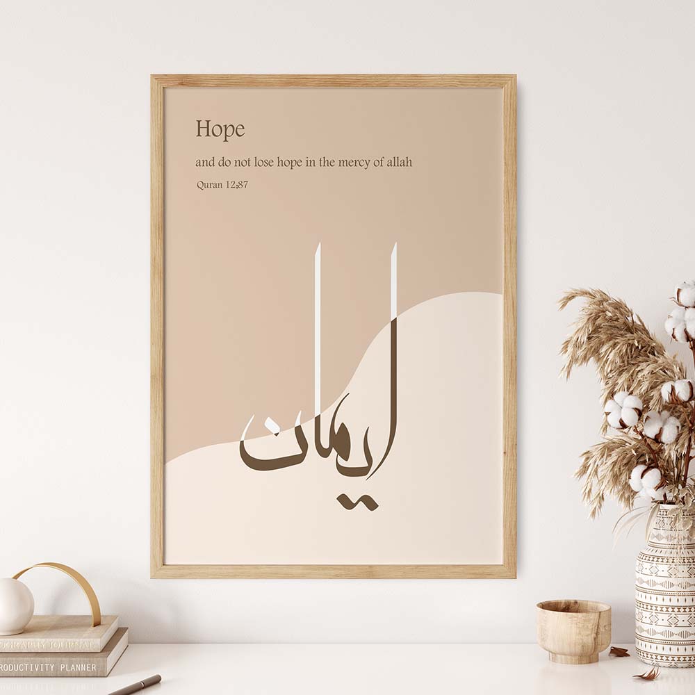 a framed poster with the word "Hope" written on it, along with Arabic calligraphy. The poster is hanging on a wall, and there is a vase of flowers and a stack of books next to it.